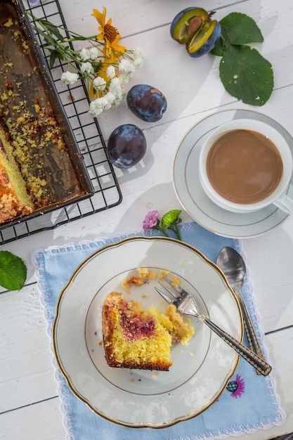 Sabroso postre con pastel de ciruelas y café en el campo