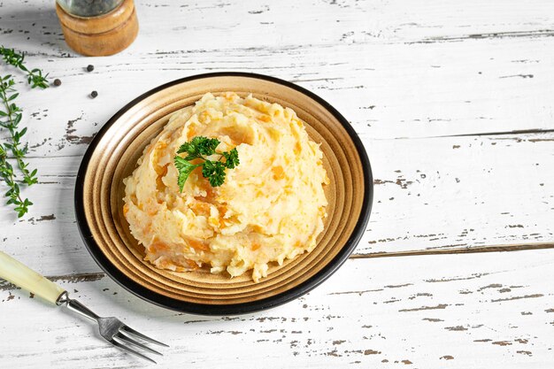 Sabroso puré de chirivía vegetariana con patatas y zanahorias sobre un fondo blanco de madera