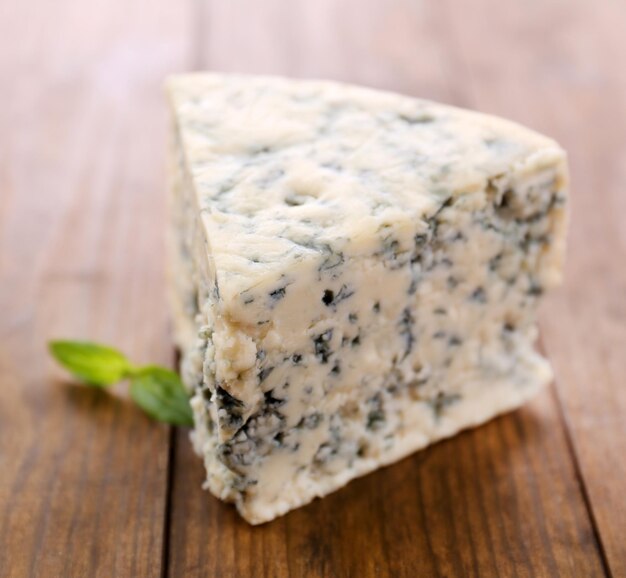 Sabroso queso azul con albahaca sobre mesa de madera