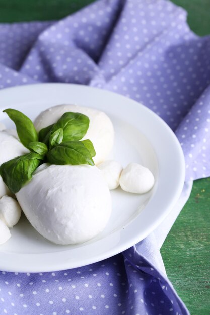 Sabroso queso mozzarella con albahaca en plato sobre fondo de madera