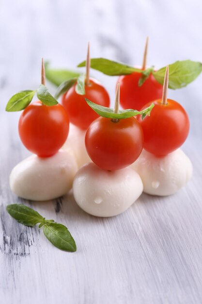 Sabroso queso mozzarella con albahaca y tomates en mesa de madera