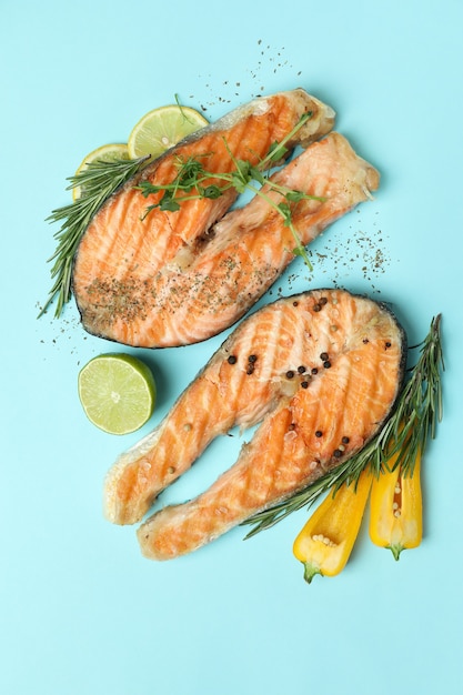 Sabroso salmón a la parrilla e ingredientes sobre fondo azul.