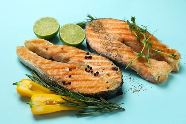 Sabroso salmón a la parrilla e ingredientes sobre fondo azul.