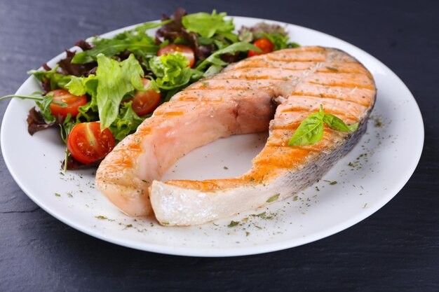 Sabroso salmón a la parrilla con ensalada en la mesa de cerca