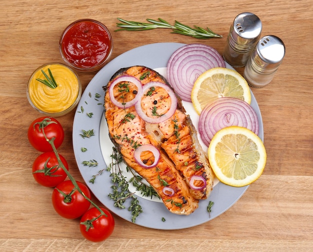 Sabroso salmón a la parrilla con verduras en mesa de madera