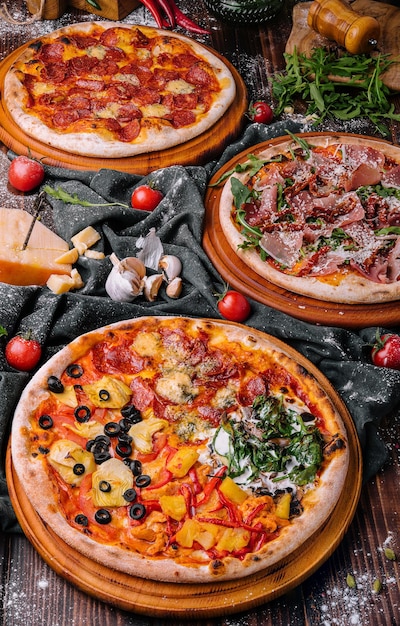 Sabroso surtido de tres pizzas sobre un fondo de madera