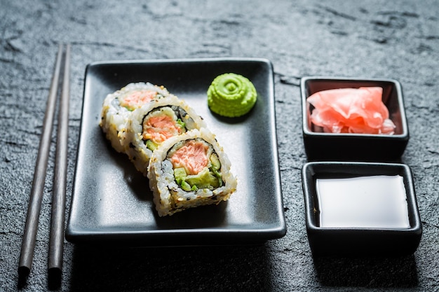 Sabroso sushi hecho de salmón y aguacate sobre roca negra