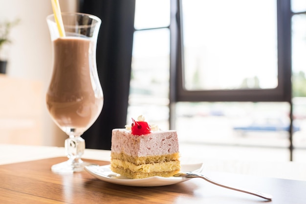 Sabroso trozo de pastel y vaso de batido en la cafetería