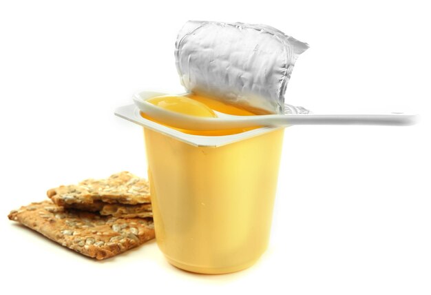 Sabroso yogur en vasos de plástico abiertos, galletas y frutas aisladas en blanco