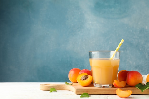 sabrosos albaricoques y jugo en mesa de madera