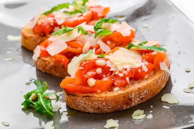 Sabrosos aperitivos italianos sabrosos, o bruschetta, en rodajas de baguette tostado con albahaca