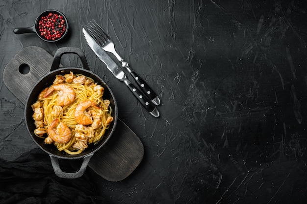 Sabrosos y apetitosos espaguetis de pasta con salsa pesto y camarones, sobre piedra negra