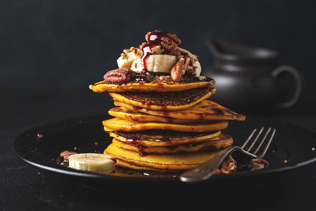 Foto sabrosos y apetitosos panqueques de calabaza con plátano, nueces y caramelo servidos en plato. de cerca