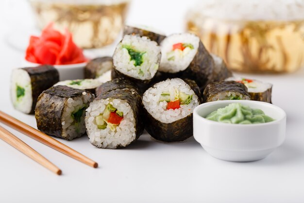 Sabrosos apetitosos rollos de sushi multicolores, servidos con salsa de soja y palillos