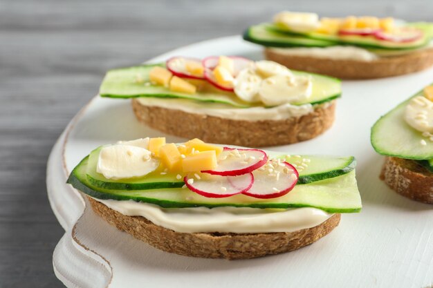 Sabrosos bocadillos con pepino fresco sobre tabla de madera