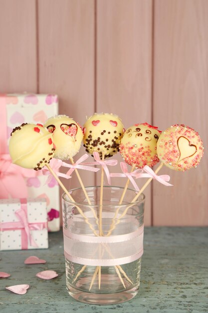 Sabrosos cake pops y regalos sobre fondo de madera