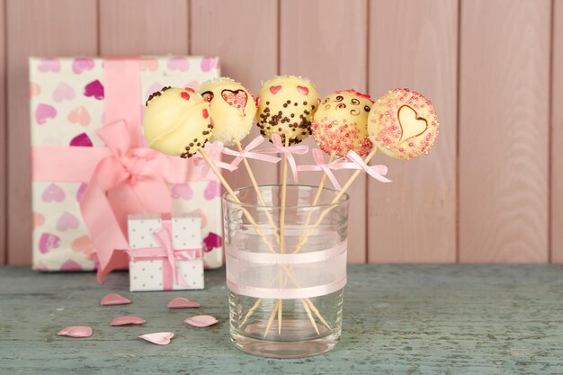 Sabrosos cake pops y regalos sobre fondo de madera