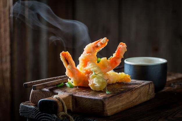 Sabrosos camarones en tempura con salsa roja sobre fondo negro