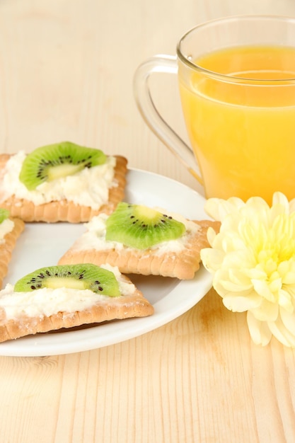 Sabrosos canapés con queso y kiwi en placa de color sobre fondo de madera