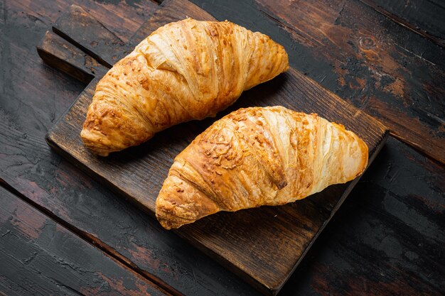 Sabrosos croissants mantecosos, sobre fondo antiguo de mesa de madera oscura, con espacio para copiar texto