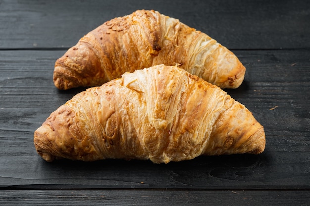 Sabrosos croissants mantecosos, sobre fondo de mesa de madera negra