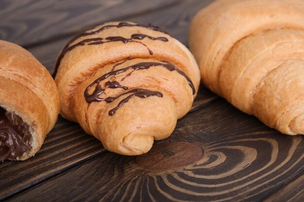 Sabrosos croissants con salsa de chocolate sobre mesa de madera