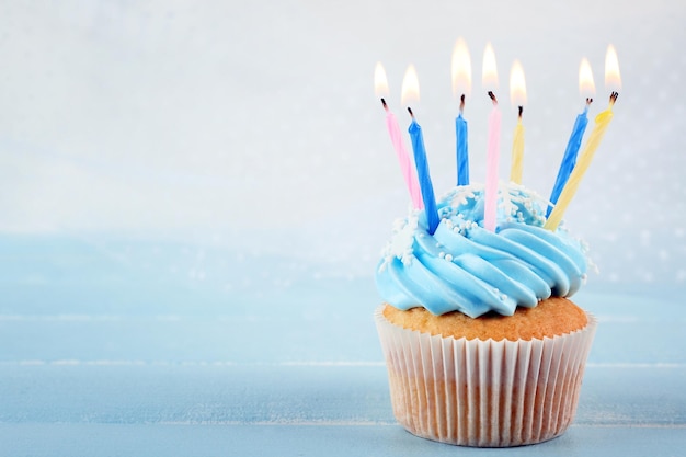 Sabrosos cupcakes azules decorados con velas sobre fondo claro