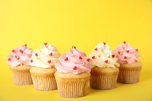 Sabrosos cupcakes con chispas en forma de corazón sobre fondo amarillo Celebración del Día de San Valentín