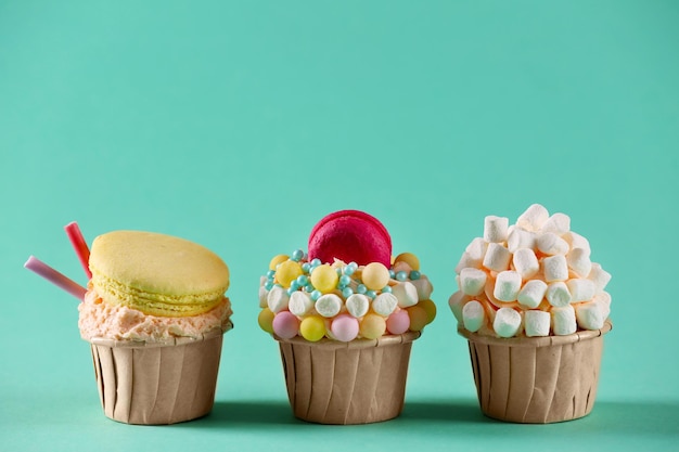 Foto sabrosos cupcakes con decoración original sobre fondo turquesa