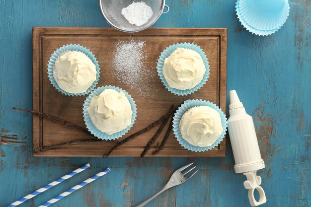 Sabrosos cupcakes de vainilla sobre tabla de madera