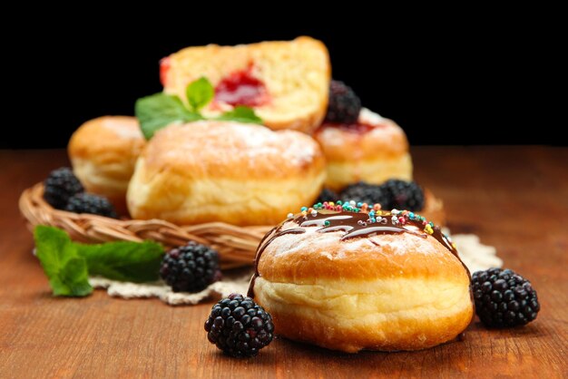 Foto sabrosos donuts con chocolate y bayas en mesa de madera