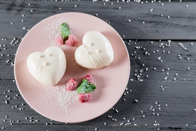 Sabrosos dulces de chocolate blanco en forma de corazón sobre fondo de madera