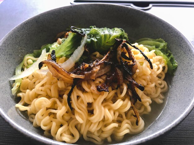 Sabrosos fideos instantáneos con verduras en un tazón en el primer plano de la mesa