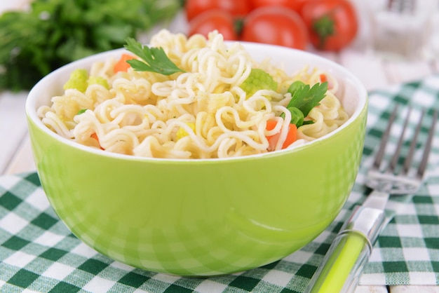 Sabrosos fideos instantáneos con verduras en un tazón en el primer plano de la mesa