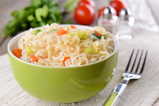 Sabrosos fideos instantáneos con verduras en un tazón en el primer plano de la mesa