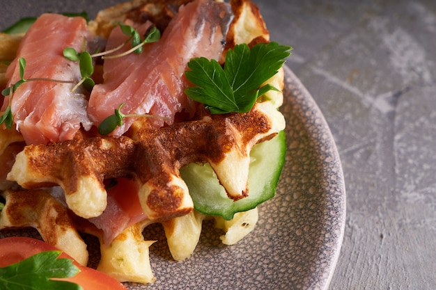 Sabrosos gofres caseros con salmón, pepino y hierbas en un plato