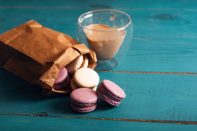 Sabrosos macarons de almendras y café con leche en la superficie de madera azul Estilo romántico vintage