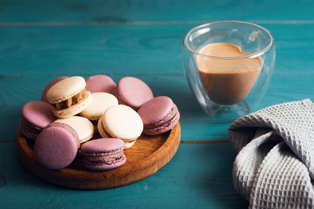 Sabrosos macarons de almendras y café con leche en la superficie de madera azul Estilo romántico vintage