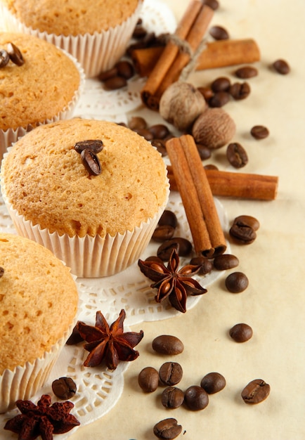 Sabrosos pasteles de muffin en arpillera, especias y semillas de café, sobre fondo beige