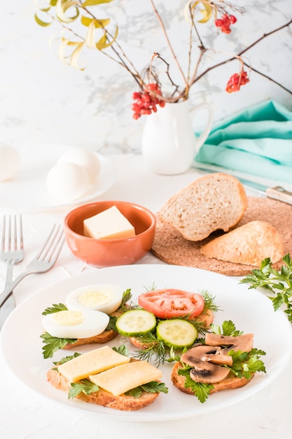 Sabrosos sándwiches en un plato y tenedores sobre una mesa.