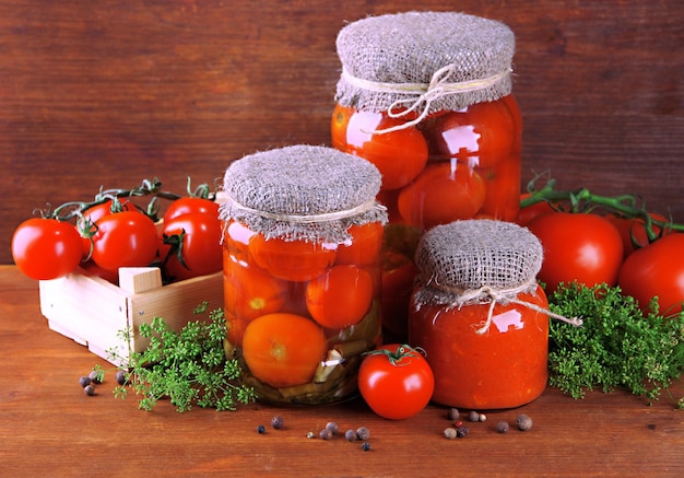 Sabrosos tomates enlatados y frescos en mesa de madera