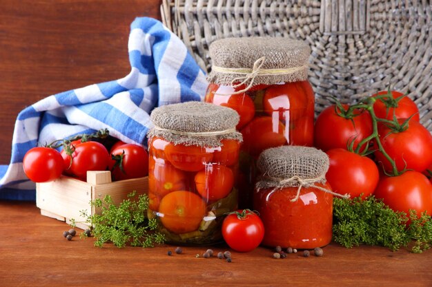 Sabrosos tomates enlatados y frescos en mesa de madera