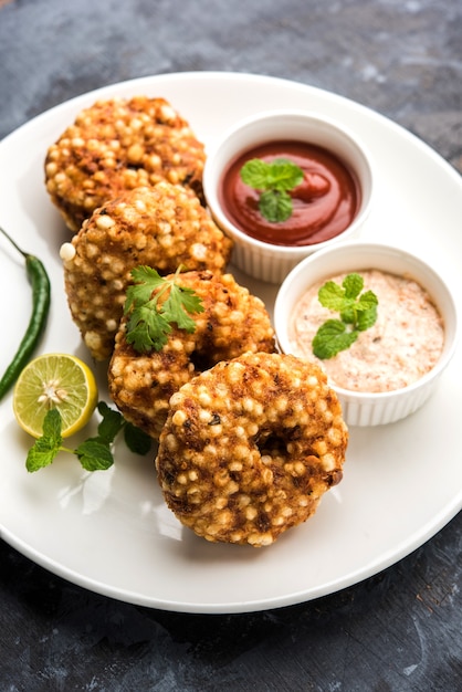 Sabudana vada ou bolo frito de sagu servido com chutney de amendoim sobre fundo temperamental, popular receita de jejum da índia.