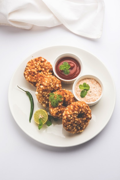 Sabudana vada ou bolo frito de sagu servido com chutney de amendoim sobre fundo temperamental, popular receita de jejum da Índia.