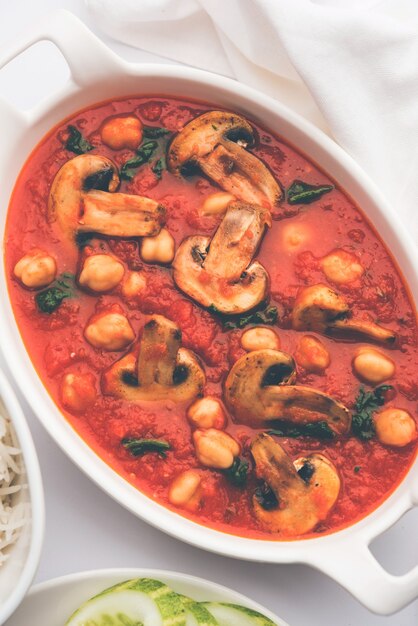 Foto sabzi de champiñones al curry de tomate con garbanzos y espinacas, menú principal indio servido con paratha y arroz blanco cocido