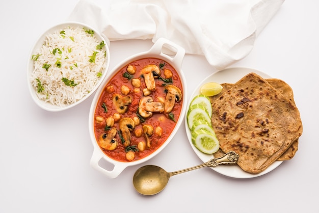 Sabzi de cogumelos ao curry de tomate com grão de bico e espinafre, prato principal indiano servido com paratha e arroz branco cozido