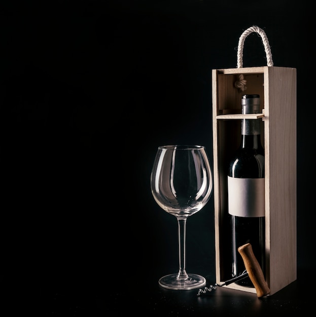 Foto sacacorchos y copa de vino cerca de arco con botella
