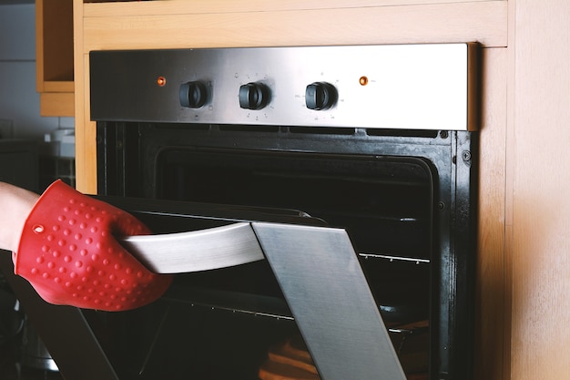 Foto sacar la bandeja cocida del horno con guantes de cocina