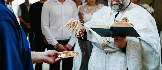 El sacerdote bendice los anillos de bodas de oro para la novia y el novio.