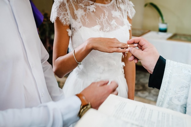 El sacerdote bendice las manos con los anillos de boda de la novia y el novio en la iglesia